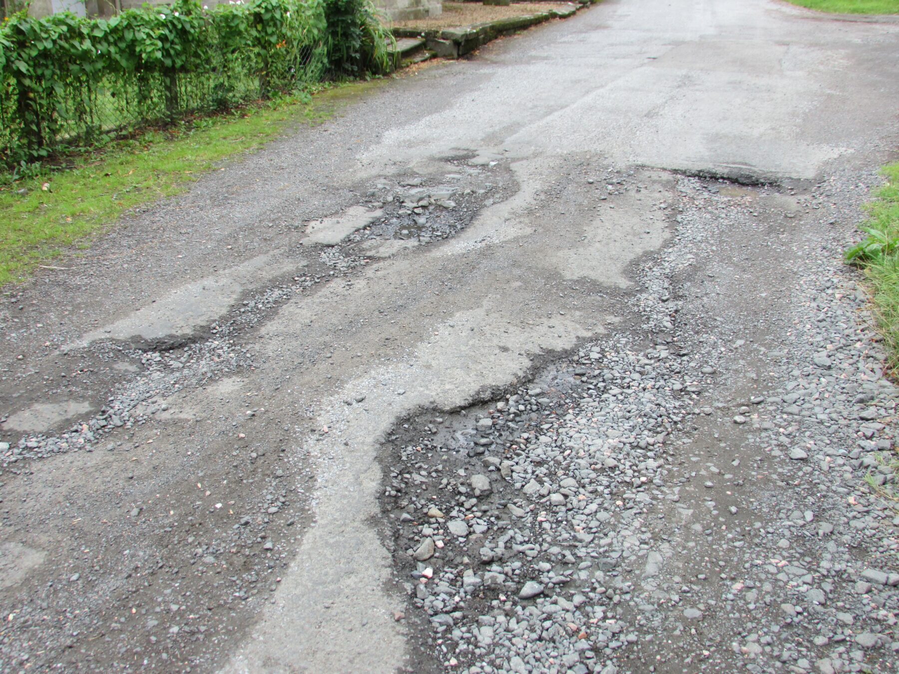 Worn asphalt pavement with surface distress, uneven texture, and exposed aggregate, illustrating the long-term effects of temperature, moisture, and seasonal weather on asphalt performance.